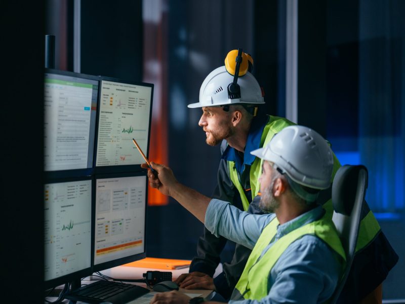 Group of operators control process on product line uses industry 4.0 and digital technology on modern factory. Two engineers follow assembly process uses SCADA system which AI technology and UI